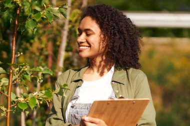 Gülümseyen kadın bahçıvan bahçe merkezinde dururken not alıyor. Yüksek kalite fotoğraf