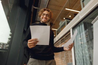 Modern ofis geçmişine bakarken belgelere bakan yakışıklı bir işadamı