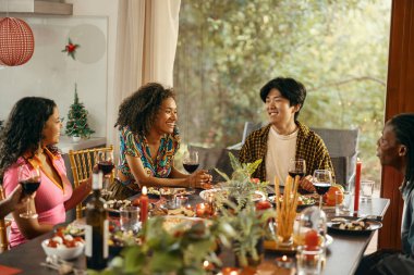 Mutlu arkadaşlar sohbetten ve ev partisinde şenlik yemeği sırasında şarap içmekten zevk alırlar.
