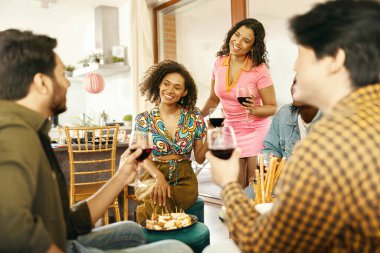 Mutlu genç arkadaşlar kırmızı şarap içiyor ve evdeki tatil partisinde eğleniyorlar.