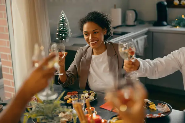 Happy young friends drinking wine and enjoying time together at holiday dinner party at home