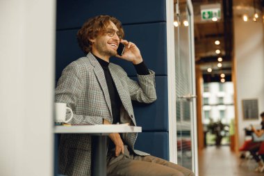 İş yerinde müşteriyle cep telefonuyla konuşan yakışıklı iş adamı 