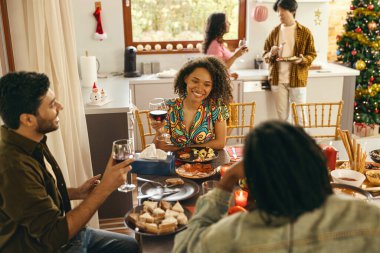 Mutlu arkadaşlar sohbetten ve ev partisinde şenlik yemeği sırasında şarap içmekten zevk alırlar.