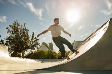 Aktif kaykaycı atlıyor ve kaykay parkında bir numara yapıyor.