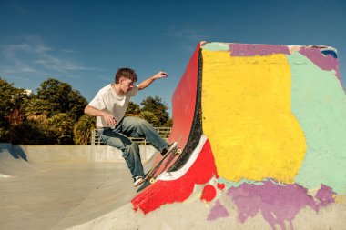 Aktif kaykaycı atlıyor ve kaykay parkında bir numara yapıyor.