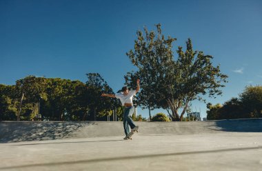 Kaykay parkında kaykay yaparken gündelik kıyafetli bir erkek kaykaycı vücudu.