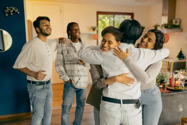Group of smiling friends happy to meet and embracing each other at home party. High quality photo