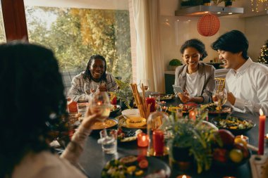 Mutlu arkadaşlar sohbetten ve ev partisinde şenlik yemeği sırasında şarap içmekten zevk alırlar.