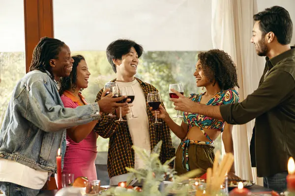 Group of smiling friends enjoying in conversation and drinking wine during Christmas party at home
