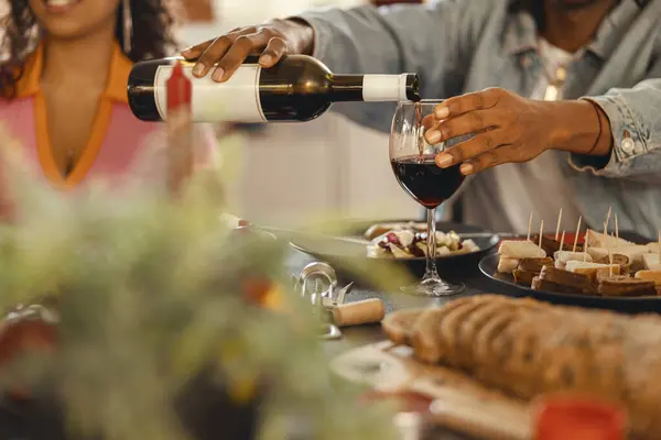 Close up of man pouring red wine into glass during festive dinner party. High quality photo