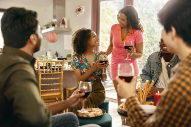 Mutlu arkadaşlar sohbetten ve ev partisinde şenlik yemeği sırasında şarap içmekten zevk alırlar.