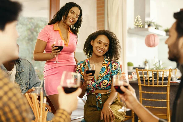 Happy young friends drinking red wine and enjoying time together at holiday party at home