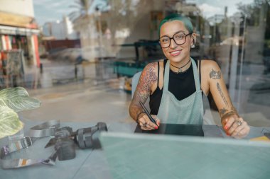 Kadın çalışan, stüdyoda fotoğraf veya dijital çizim için grafik tableti ve dizüstü bilgisayar kullanır