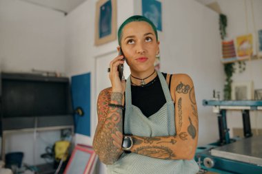 Kadın tasarımcı, tasarım stüdyosunda çalışırken cep telefonu kullanıyor. Yüksek kalite fotoğraf