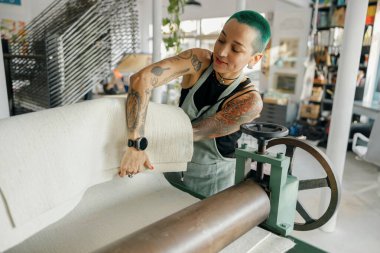 Önlüklü kadın işçi tasarım stüdyosunda çalışırken özel ekipman kullanır. Yüksek kalite fotoğraf