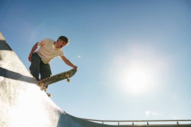 Güneşli bir günde kaykay parkında kaykay yapan aktif bir genç. Ekstrem spor konsepti