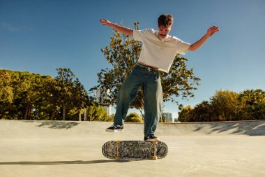 Güneşli bir günde kaykay parkında kaykay süren heyecanlı genç adam. Ekstrem spor konsepti