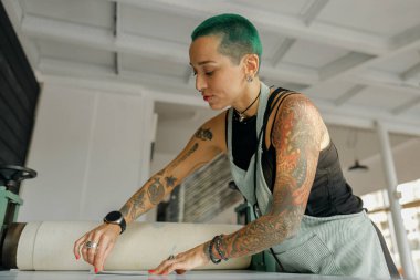 Önlüklü kadın işçi tasarım stüdyosunda çalışırken özel ekipman kullanır. Yüksek kalite fotoğraf