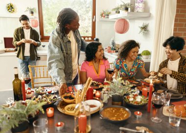 Mutlu arkadaşlar sohbetten ve ev partisinde şenlik yemeği sırasında şarap içmekten zevk alırlar.