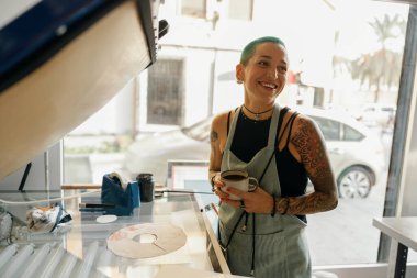 Bir atölyede baskı makinesi kullanırken ekran yazdırma filmi hazırlayan yaratıcı kadın işçiler