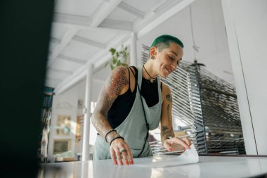 Bir atölyede matbaa makinesinde kullanmak üzere ekran yazdırma filmi hazırlayan yaratıcı kadın işçiler