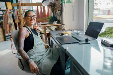 Kadın çalışan, stüdyoda fotoğraf veya dijital çizim için grafik tableti ve dizüstü bilgisayar kullanır