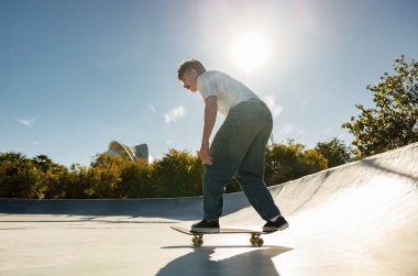 Kaykay parkında kaykay yaparken gündelik kıyafetli bir erkek kaykaycı vücudu.