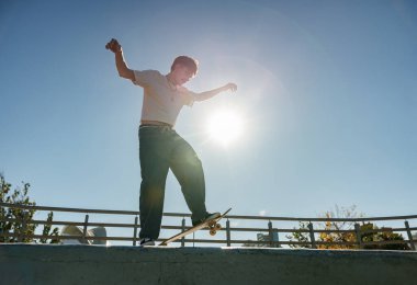 Aktif kaykaycı atlıyor ve kaykay parkında bir numara yapıyor.