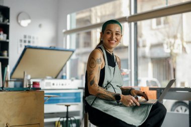 Tasarım stüdyosunda dizüstü bilgisayarı olan yaratıcı bir kadın işçi.