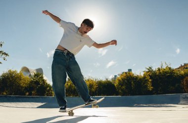 Aktif kaykaycı atlıyor ve kaykay parkında bir numara yapıyor.