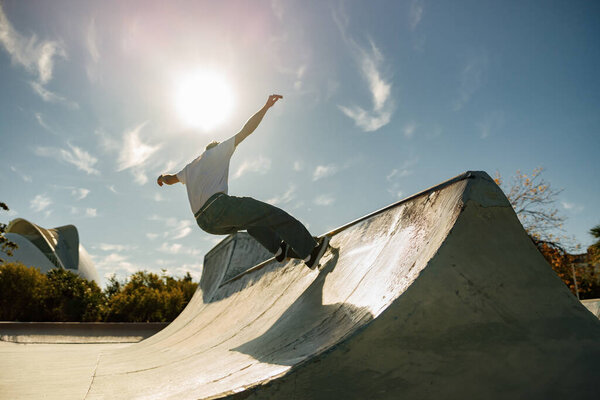 Активный скейтбордист прыгает и выполняет трюк в рампе скейт-парка
