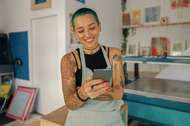 Kadın tasarımcı, tasarım stüdyosunda çalışırken cep telefonu kullanıyor. Yüksek kalite fotoğraf