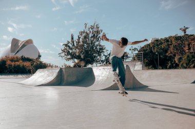 Aktif kaykaycı atlıyor ve kaykay parkında bir numara yapıyor.