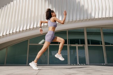Spor giyim sektöründe genç bir kadın modern binalarda çalışıyor. Etkin yaşam tarzı kavramı