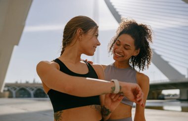 Genç, formda kadınlar akıllı kasetlere bakıyor ve yanmış kalorileri sayıyor. Sağlıklı yaşam konsepti