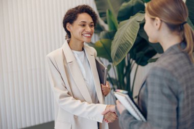 Güzel bayan girişimci, iş yerinde el sıkışan partneriyle başarılı bir anlaşma yapıyor.