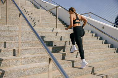 Spor giyim sektöründe genç aktif bir bayan sporcu sabahın erken saatlerinde merdivenlerde koşuyor.