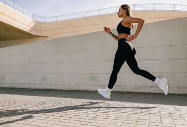 Spor giyim sektöründe genç bir kadın modern binalarda çalışıyor. Etkin yaşam tarzı kavramı