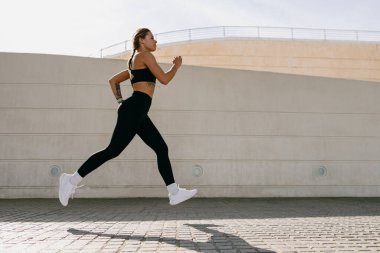 Spor giyim sektöründe genç bir kadın modern binalarda çalışıyor. Etkin yaşam tarzı kavramı