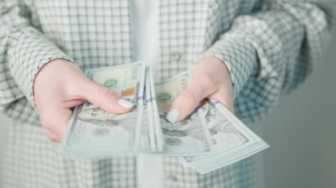 Bir iş kadınının detaylı bir çekimi titizlikle Amerikan dolarlarını sayıyor, ayrıntılı finansal organizasyonu vurguluyor ve...