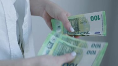 Bu resim, bir iş kadınının Avrupa banknotlarını sayarak profesyonel bir ortamda mali yönetim ve para yönetimi konusuna ayrıntılı bir dikkat gösterdiğini gösteriyor.