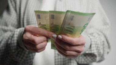 Avro banknotlarını sayarken, para yönetimi ve bütçe kavramlarını vurgulayan bir kadının ellerini gösteren net bir görüntü.