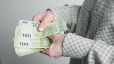 Zarif bir spor ceketli zarif bir iş kadını, 100 Euro 'luk banknotların tomarlarını tutuyor, mali hünerini ve para yönetimi detaylarına olan ilgisini gösteriyor..