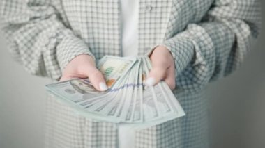 Bu görüntü, titizlikle bir yığın Amerikan doları banknotunu sayan şık bir ceketle finans yönetimi ve kontrolü vurgulayan bir iş kadınını yakalıyor.