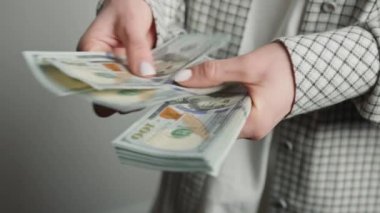 Dinamik bir yakın plan çekimde yakalanan bu görüntüde, çeşitli uluslararası para birimlerini idare etmedeki yeterliliğini vurgulayan ve her iki ABD doları banknotlarını ustaca sayan bir iş kadını yer alıyor.