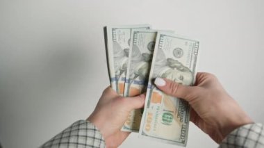 Bu görüntü, Amerikan dolarlarını tasnif ederken bir iş kadınının ellerine odaklanıyor. Finansal operasyonlara günlük katılımını ve titiz para birimini gösteriyor.
