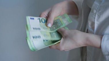 Avro banknotlarını ustalıkla idare eden, nakit işlemleri ve döviz kurlarını vurgulayan bir kadının ellerini gösteren ayrıntılı bir resim.
