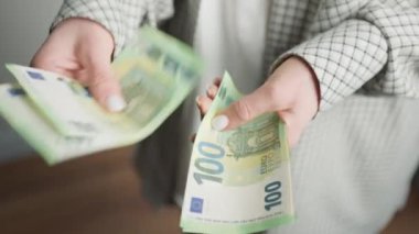Görüntü, 100 Euro 'luk banknotları aktif olarak sıralayan bir iş kadınının ellerini yakalıyor ve mali işlemler ve para yönetimi konusundaki verimliliğini gösteriyor.