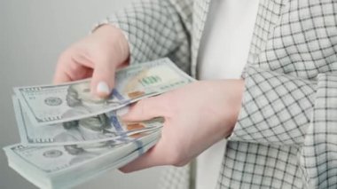 Ekose takım elbiseli profesyonel bir kadının birçok Amerikan dolarını titizlikle idare ettiği yakın plan bir fotoğraf.