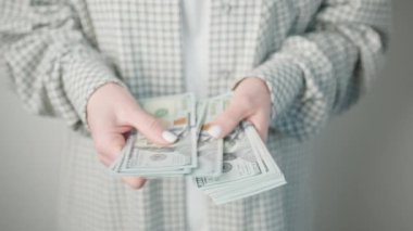 Kadının eli bir yığın parayı tutuyor, parmakları nazikçe banknotları tutuyor. Bileğine bir bilezik takılmış, jestine biraz zarafet katıyor.